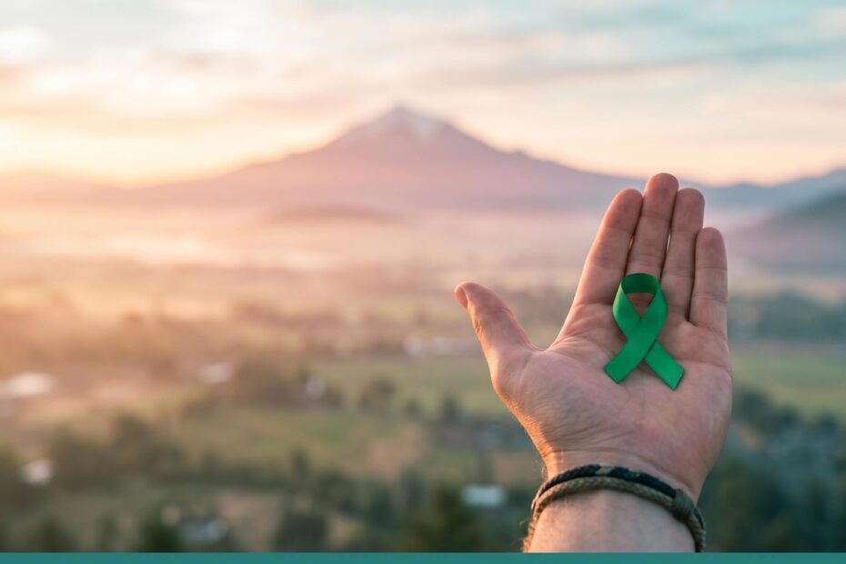 Sunrise over the Rogue Valley with a hand holding a green awareness ribbon